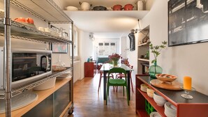 Een keuken met een koelkast, oven en planken met servies.