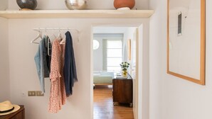 Een hal met een kledingrek, een hoed op een tafel en een houten dressoir.