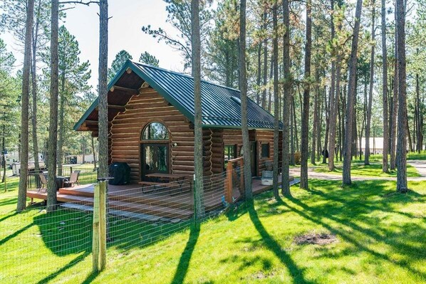 A log cabin with a porch, a deck, and a fenced area. - Pine Cabin- Log cabin close to Custer (Custer)