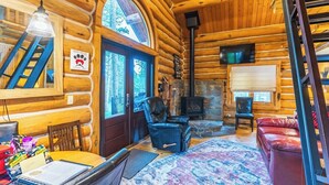A log cabin interior with a stone fireplace, leather furniture, and a staircase. - Pine Cabin- Log cabin close to Custer (Custer)