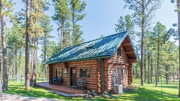 A log cabin with a porch, a covered outdoor seating area, and a view of a forested area. - Pine Cabin- Log cabin close to Custer (Custer)