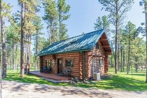 A log cabin with a porch, a covered outdoor seating area, and a view of a forested area. - Pine Cabin- Log cabin close to Custer (Custer)