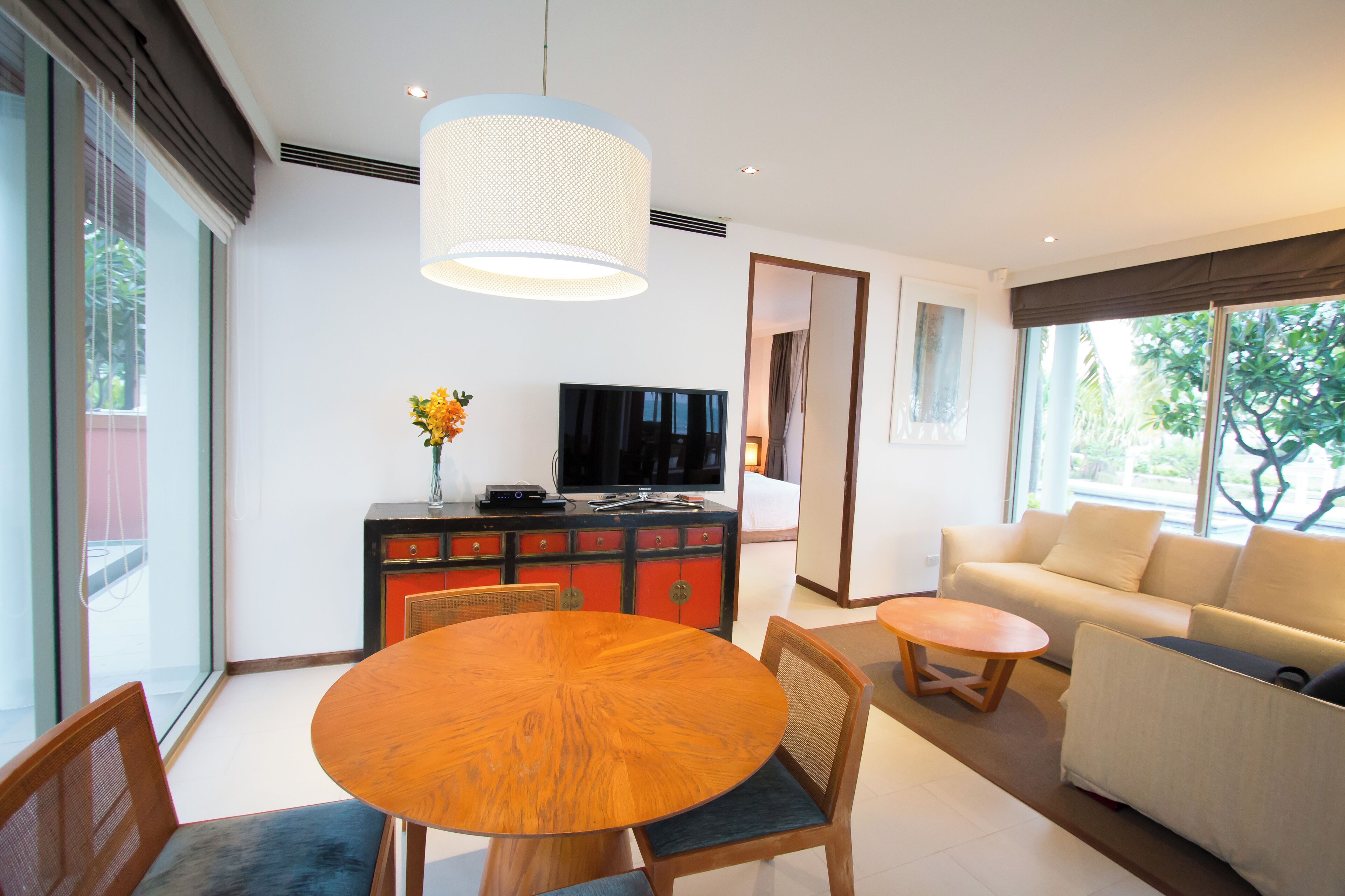A modern living room with a round wooden table, a sofa, and a television.