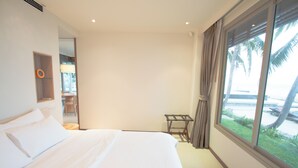 Habitación de hotel con una cama grande, una mesita pequeña y una ventana con vistas a palmeras.