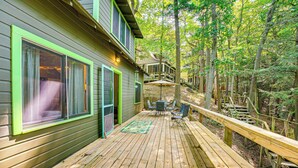 Une terrasse en bois comprenant un espace repas, un coin salon extérieur abrité et un escalier menant à un deuxième niveau.