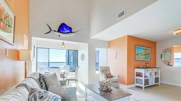 A spacious living area with a sofa, coffee table, and a view of the ocean through large windows.