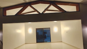 Ein geräumiger Raum mit großem Fenster, einer Tür und einer Decke mit Holzbalken.