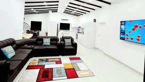 Ein modernes Wohnzimmer mit einem Ecksofa, einem farbenfrohen Teppich und einem an der Wand befestigten Flachbildfernseher.