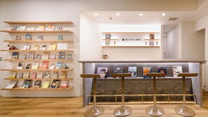 Una librería con numerosas estanterías llenas de libros y una zona de bar con taburetes.