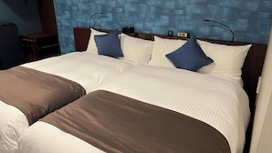 Habitación de hotel con dos camas, una mesita de noche, una lámpara y un reloj en la pared.