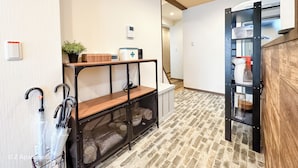 A hallway with a wooden bench, a small table with a plant, a digital clock, and a wall-mounted thermostat.