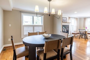 A dining area with a round table, six chairs, a chandelier, and a window with blinds. - All Newly-Designed Water Views, Expansive Yard, Steps to Restaurants and Downtown Annapolis (Annapolis)