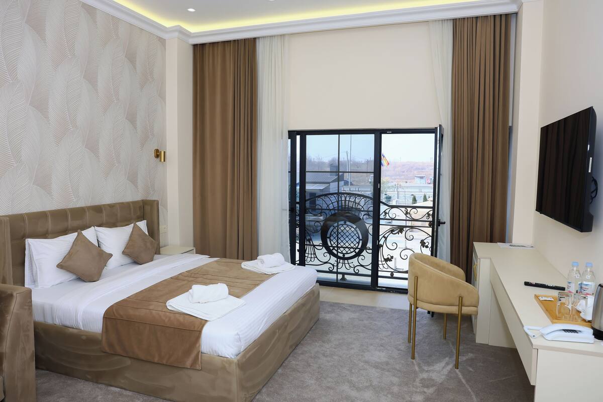 Une chambre d’hôtel avec un grand lit, un bureau, une chaise et un balcon avec vue.