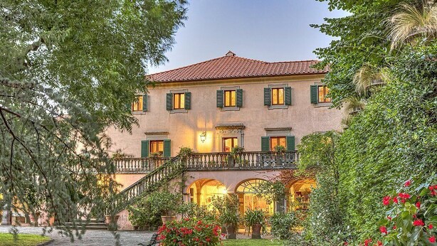 A two-story building with a red-tiled roof, green shutters, and a central courtyard with a bench and potted plants. - Villa Margaret: A splendid nineteenth-century three-story historical villa surrounded by the greenery, with Free WI-FI. (Pontremoli)