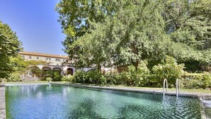 A clear swimming pool surrounded by lush greenery and a building with arched windows in the background. - Villa Margaret: A splendid nineteenth-century three-story historical villa surrounded by the greenery, with Free WI-FI. (Pontremoli)