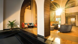 Un'ampia hall con un'imponente scalinata, zone relax con comodi posti a sedere e un soffitto alto illuminato da luce naturale.