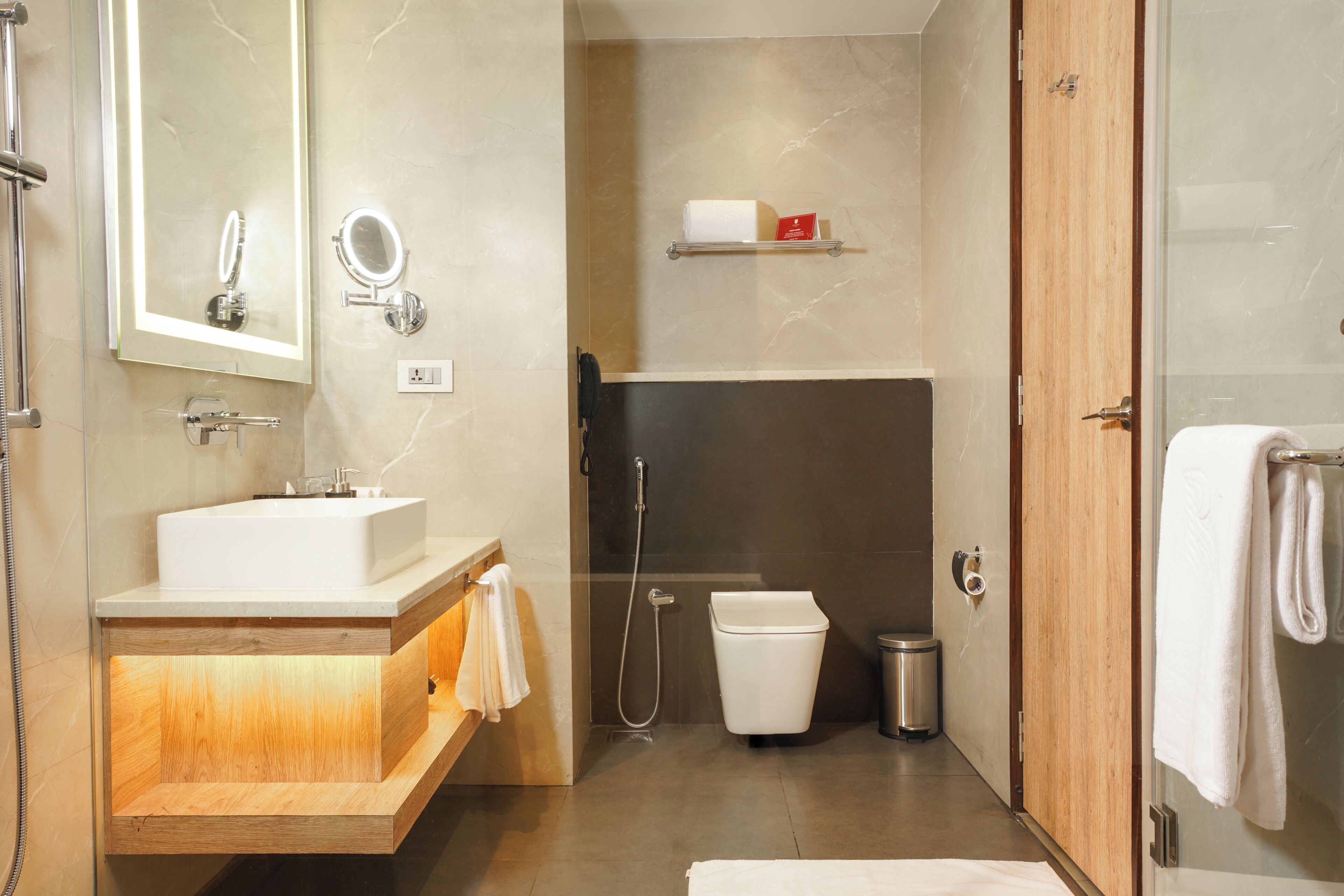 A modern bathroom with a sink, mirror, shower, and toilet.