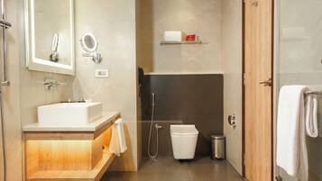 A modern bathroom with a sink, mirror, shower, and toilet.