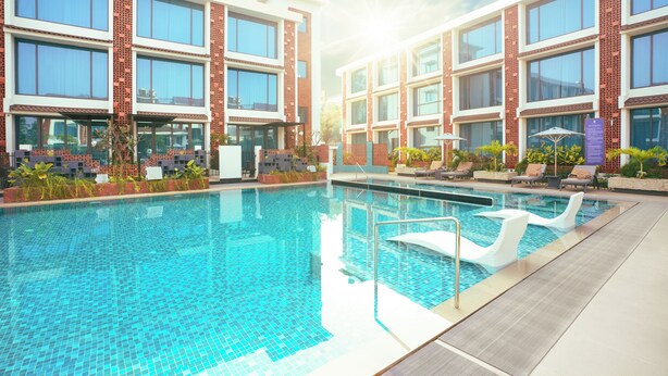 Una piscina con acqua cristallina, circondata da edifici moderni con ampie finestre e facciate in mattoni.