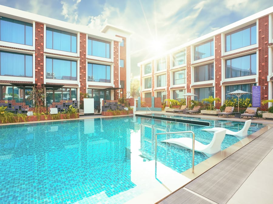 Una piscina al aire libre, sombrillas, sillones reclinables de piscina