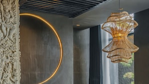 A modern living room with a sectional sofa, a dark coffee table, and a unique woven light fixture. - Nebius Villa by Betterplace (Ungasan)