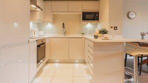 A modern kitchen with a microwave, oven, and bar stools.
