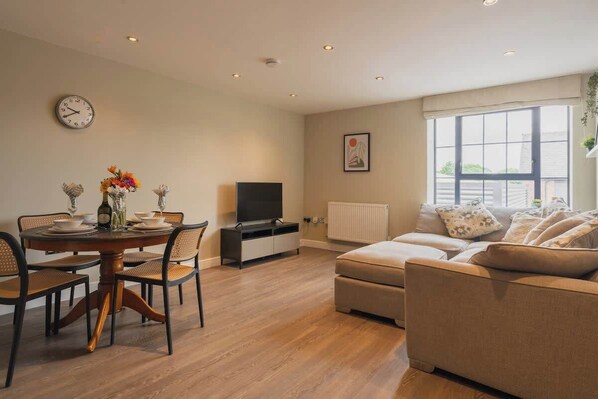 Una sala de estar con una mesa de comedor, sofá, televisor y una ventana con vistas.