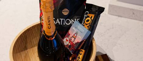 A wooden bowl containing a bottle of Canti Prosecco, a black bag with the Fox logo, and a blue box of Chester playing cards.