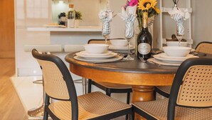 A round dining table with white plates, a bottle of wine, and a vase with flowers.