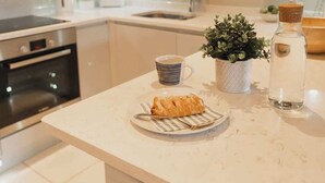 A kitchen counter with a plate of food, a mug, a potted plant, and a bottle.