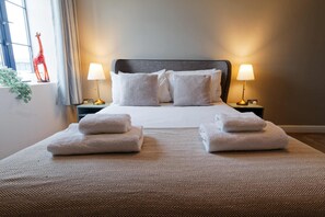 Una habitación de hotel con una cama grande, dos lámparas de noche, un ventanal con vistas y una estatua decorativa de una jirafa.