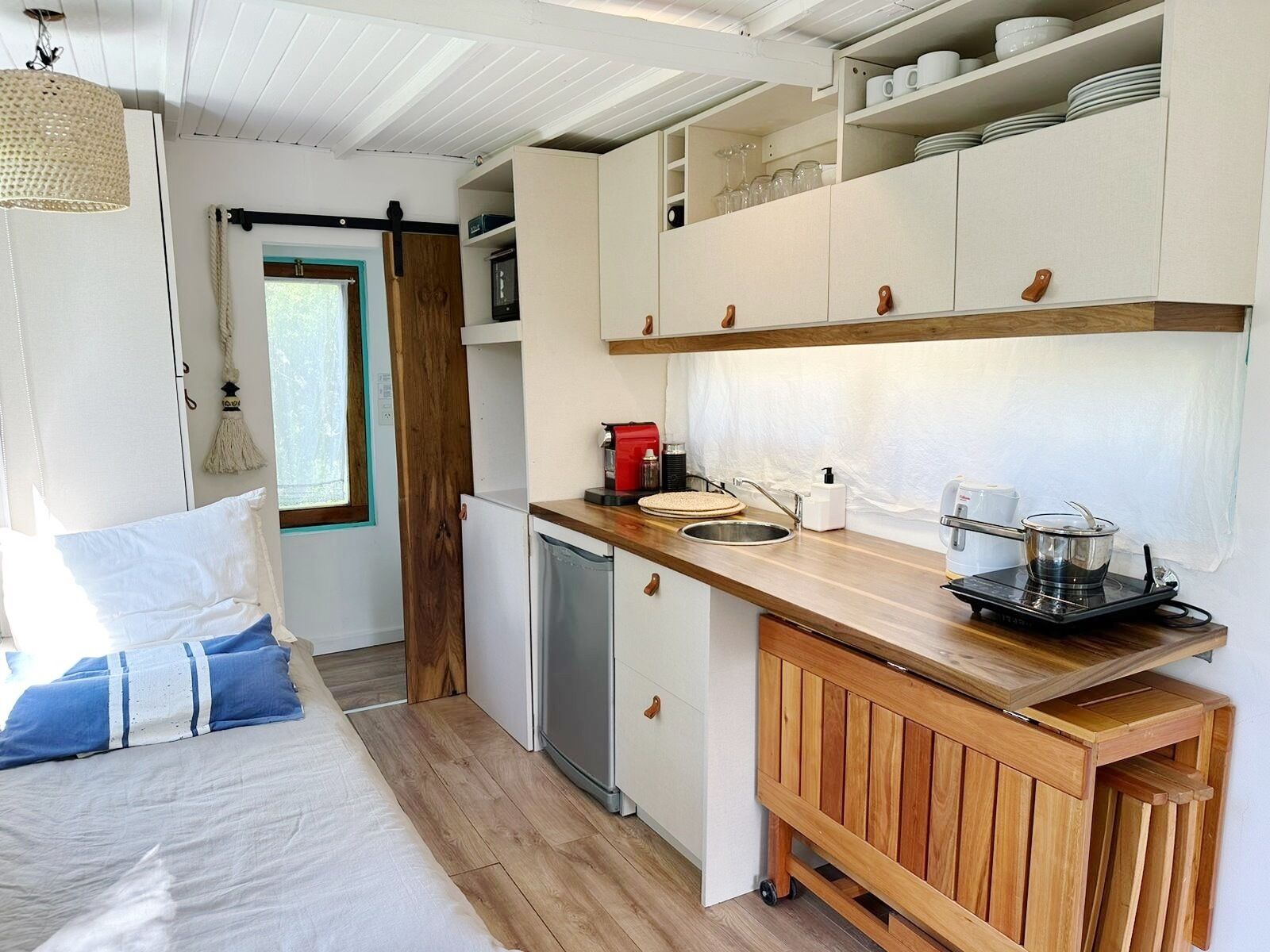 Una cocina compacta con muebles de madera, un lavamanos y una estufa portátil.