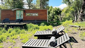 A cabin with a deck, two chairs, and a table with a blanket.