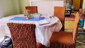 Comedor con una mesa redonda cubierta con mantel blanco, rodeado de sillas tapizadas en color naranja.