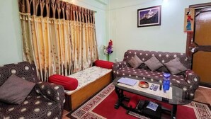 Una sala con sofás estampados, una mesa de centro con objetos y una cortina con diseño floral.