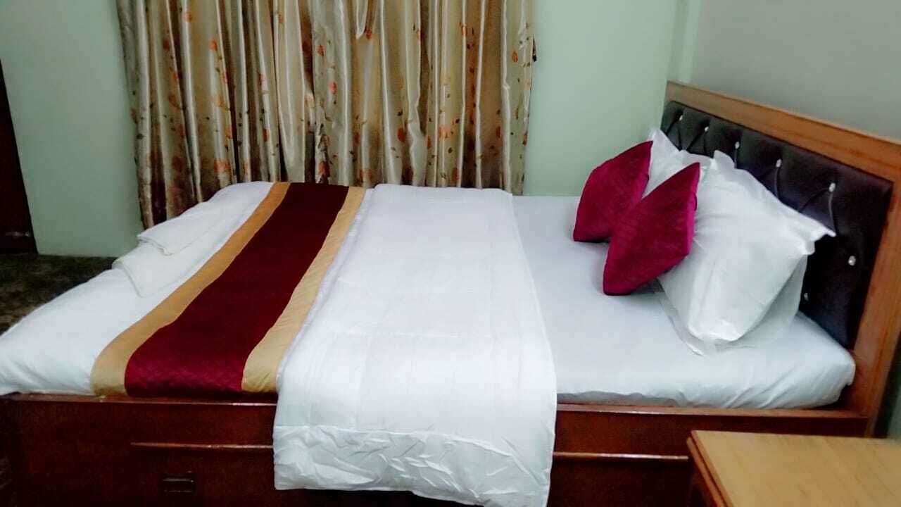 A neatly made bed with a striped blanket, two pillows, and a wooden headboard.
