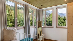 A bedroom with a bed, a bench, a mirror, and large windows with a view of greenery and mountains. - Apartment 'Villa Stumm' with Mountain View, Shared Terrace and Wi-Fi (Stumm)