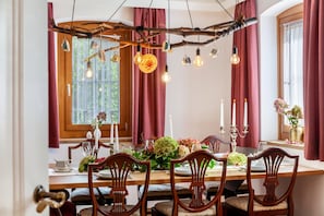 A dining area with a wooden table, chairs, and a unique branch chandelier.