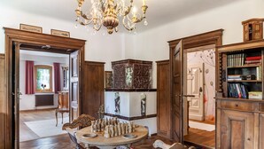 A room with a chandelier, a chessboard, a fireplace, and a bookshelf. - Apartment 'Villa Stumm' with Mountain View, Shared Terrace and Wi-Fi (Stumm)