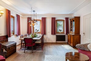 Ein Essbereich mit einem Holztisch, gedeckt für vier Personen, umgeben von Stühlen, einer Kandelaber und einer großen Holzspeisekammer.