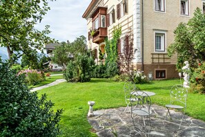 Ein Innenhof mit einem Steinweg, einem kleinen Garten und einem Gebäude mit einem Balkon.