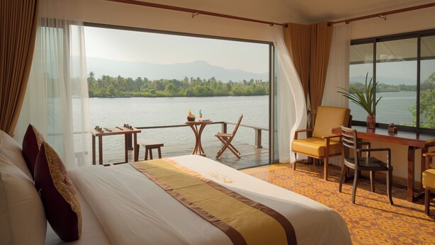 Ein Hotelzimmer mit einem großen Bett, einem Schreibtisch, einem Stuhl und Blick auf einen See.
