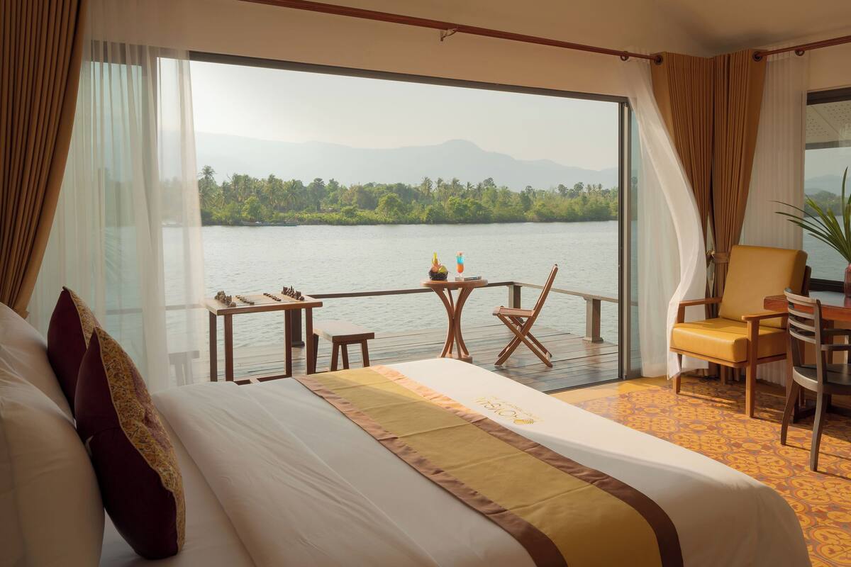 Ein Hotelzimmer mit einem großen Bett, einem Schreibtisch, einem Stuhl und Blick auf einen See.