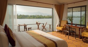 Ein Hotelzimmer mit einem großen Bett, einem Schreibtisch, einem Stuhl und Blick auf einen See.
