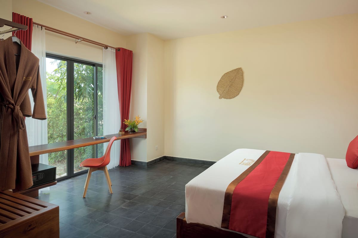 Ein Hotelzimmer mit Bett, Schreibtisch, Stuhl und einem fenster mit Vorhängen.