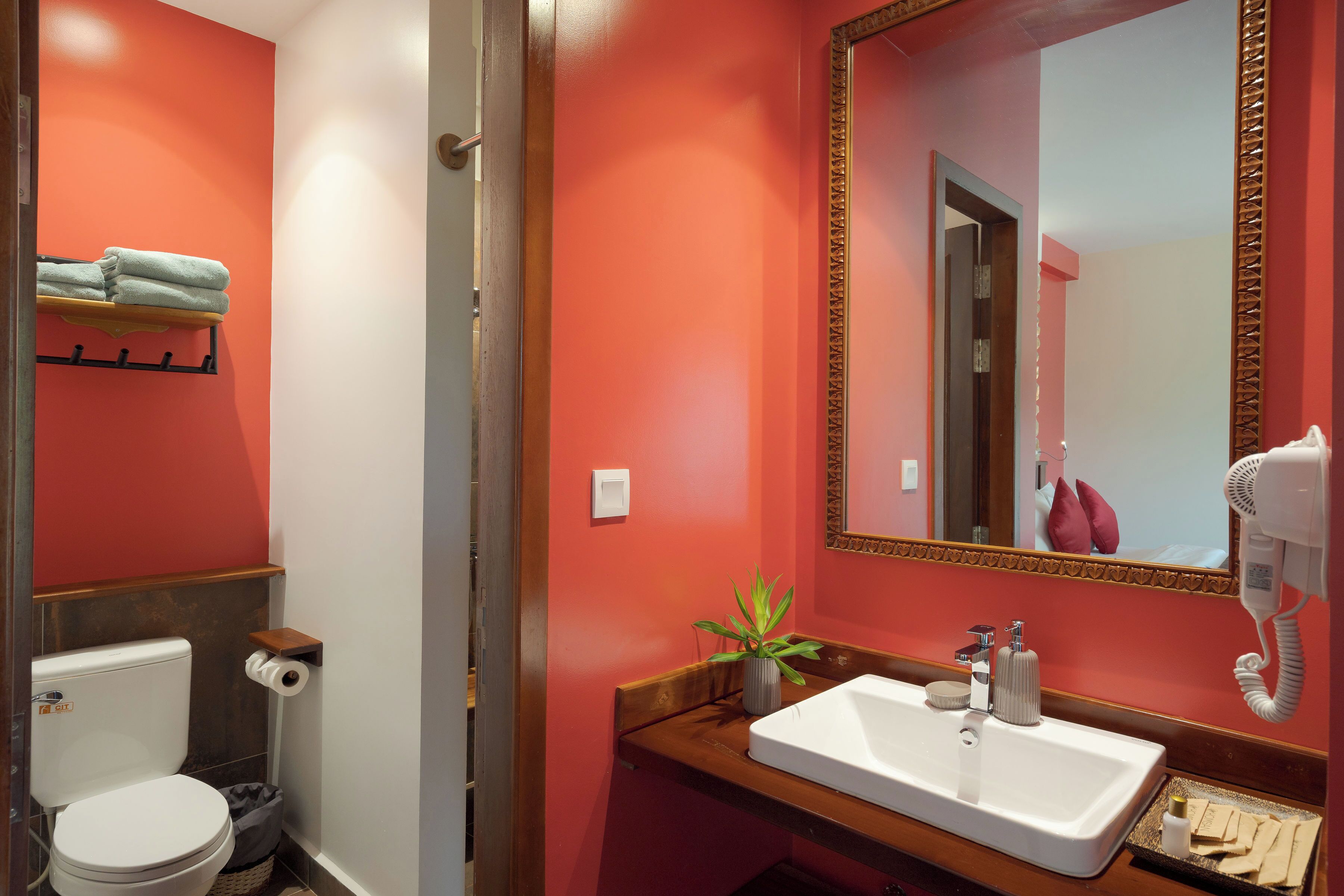 A bathroom with a white sink, a mirror with a gold frame, a hairdryer, and a towel rack with folded towels.