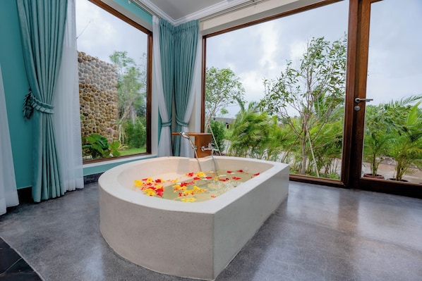Une salle de bain moderne avec une baignoire sur pieds, de grandes fenêtres et une vue sur la verdure.