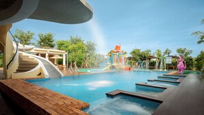 Ein Schwimmbecken mit Wasserrutsche, Whirlpool und überdachtem Bereich mit Treppe.