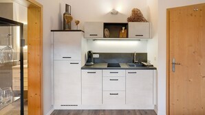 A compact kitchen with white cabinets, a black countertop, and a wooden door.