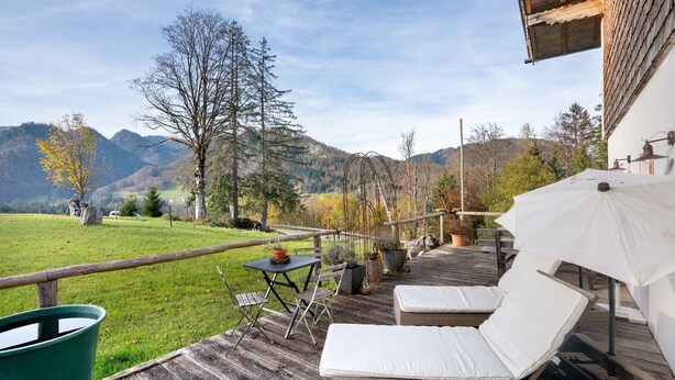 A wooden deck with outdoor seating, a table, and potted plants. - Apartment 'Ferienwohnung Unternberg' with Mountain View, Shared Terrace and Wi-Fi (Ruhpolding)